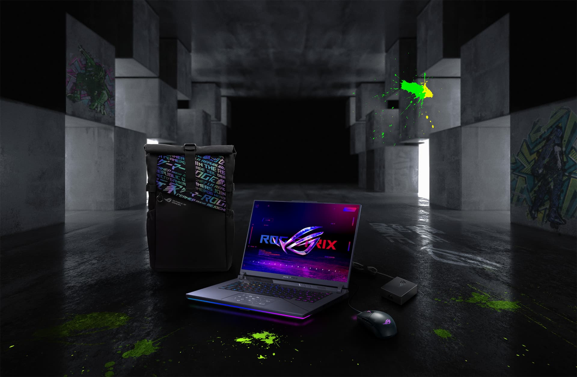 Dans un grand espace souterrain, de gauche à droite : un sac à dos ROG, un G16, une souris ROG Strix Gladius III et un adaptateur 100W.