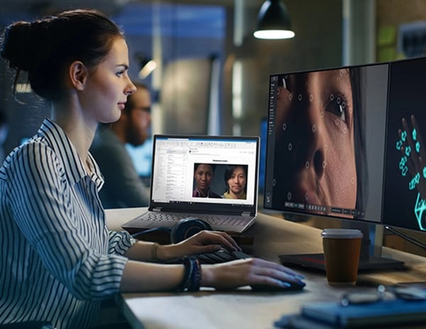 Graphic designer looking at close-up of image on large monitor, next to an opened Lenovo ThinkPad P16 Gen 2 (16″ Intel) laptop 